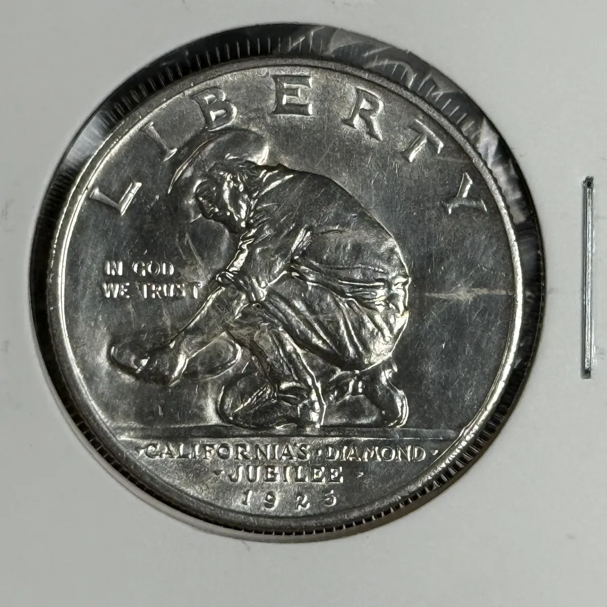 Obverse of a 1925-S California Diamond Jubilee commemorative half dollar showing a kneeling gold prospector